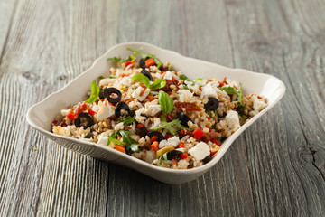 Trendy lunch with red rice, a mix of groats and vegetables. Front view. Served in white bowl on grey wooden background.