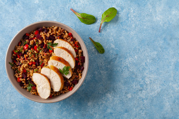 Trendy lunch with cereal, beetroot and chicken. Served in a bowl on a blue painted background. Top view.