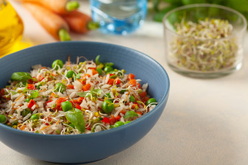 Trendy lunch with rice and vegetables. Served in a blue bowl, on a bright painted background. Front view.