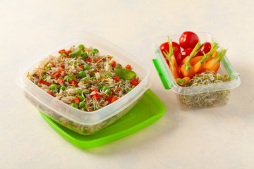 Trendy lunch with rice and vegetables. Served in a portable box on a bright painted background. Perfect for work or school. Front view.
