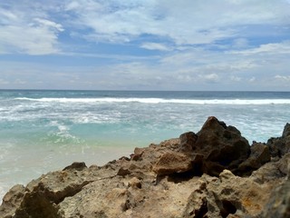 Beach with rocks, waves and blue sky. The beautiful Sanggar beach in Tulung Agung, East Java, Indonesia.