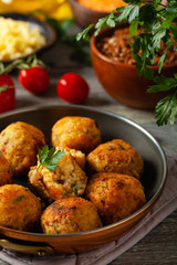 Lentil and millet meatballs. Served on tomato salsa with buckwheat. Gray plate, wooden boards in the background. Front view.