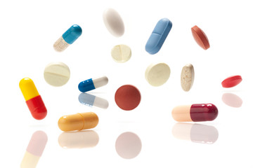 Medical pills jumping in air on white background.