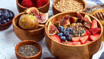 Healthy breakfast and breakfast ingredients, oatmeal with fruits and berries, figs, blueberries, strawberries, flax and chia seeds, honey.