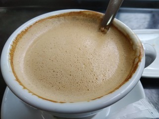 cup of coffee with cream on wooden background