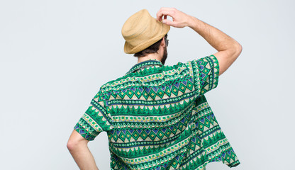 young tourist man thinking or doubting, scratching head, feeling puzzled and confused, back or rear...