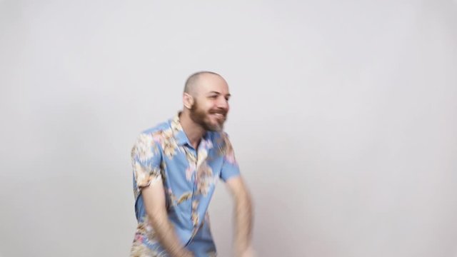 Happy bearded bald man dancing solo jazz on white background. Cheerful tourist wearing hawaiian shirt smiling and having fun.