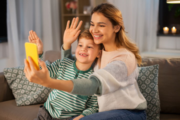 family, technology and people concept - happy smiling mother and little son with smartphone having video call and waving hands at home