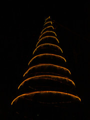 Neon Christmas tree with yellow spiral lights on a black background
