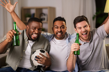 friendship, sports and entertainment concept - happy male friends with soccer ball and beer supporting football team at home