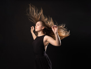 Woman on a black background in the weightlessness of flying hair in the air