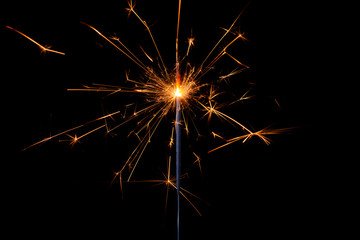 Shiny sparkler with lots of sparks burning bright isolated on black background.
