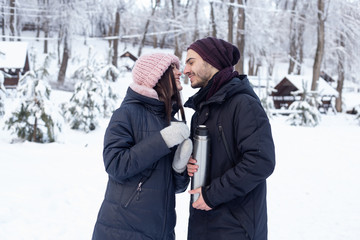 couple pouring tea from a thermos in winter park