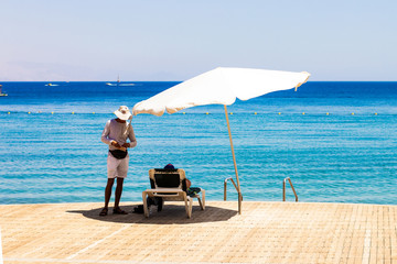 beach resort hotel waterfront space wooden deck floor Red sea beach deck chair umbrellas and...