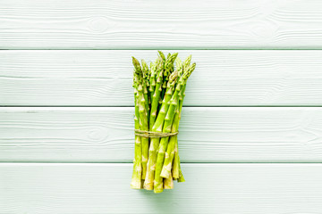 Bunch of asparagus steams on green wooden background top-down copy space
