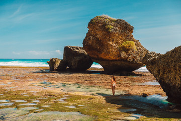 Fototapeta premium Attractive woman in bikini posing at ocean beach near rocks