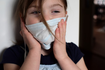 Little girl presses a medical mask to her face. Close-up portrait.