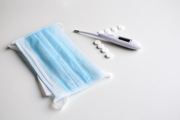 Medical mask, thermometer and pills. Concept: diagnosis, treatment and prevention of viral diseases.