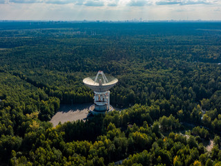 Big radio telescope in center for long-distance space communications, satellite antenna in forest. Aerial photography