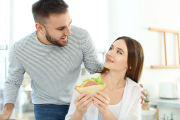 Happy couple with tasty sandwich at home