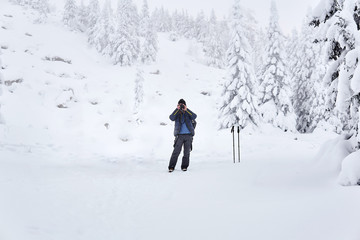 Fototapeta na wymiar man traveler photographs nature in the winter mountains
