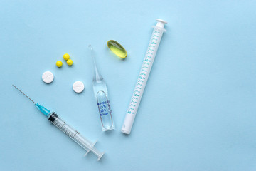 A needle with drugs lie on a blue background flat lay items