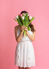 Young Girl Hiding Face Behind Bouquet Of Tulips In Her Hands