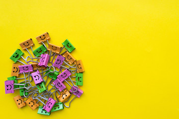 Colorful paperclips lie on yellow background