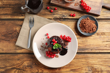 Delicious warm chocolate lava cake with mint and berries on wooden table, flat lay
