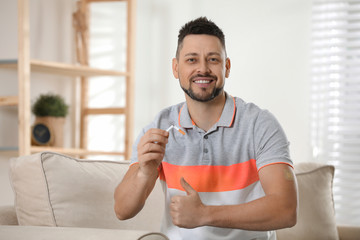 Happy man with nicotine patch and cigarette at home