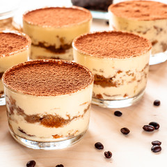classical tiramisu dessert in a glass sprinkled with cocoa and decorated with coffee beans on a dark background, luxury dessert