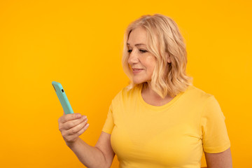 Pretty adult lady in bright clothes watching camera and posing with blue phone