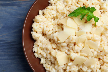 Delicious risotto with cheese on blue wooden table, closeup