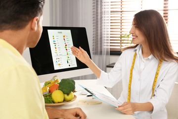 Young nutritionist consulting patient at table in clinic