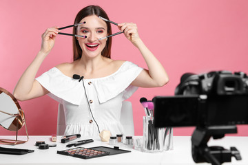 Beauty blogger recording makeup tutorial on pink background
