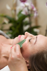 Woman having an gua sha facial massage with natural jade stone massager