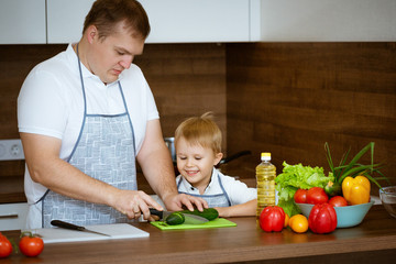 Dad and son preparing a salad in the kitchen , the concept of family cooking