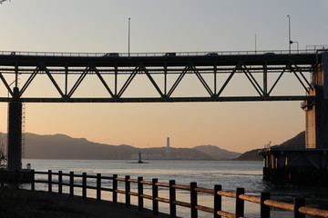 Fototapeta na wymiar 夕景の海と橋と、橋を渡る車