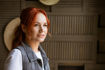 Portrait of a beautiful red haired woman looking towards the window