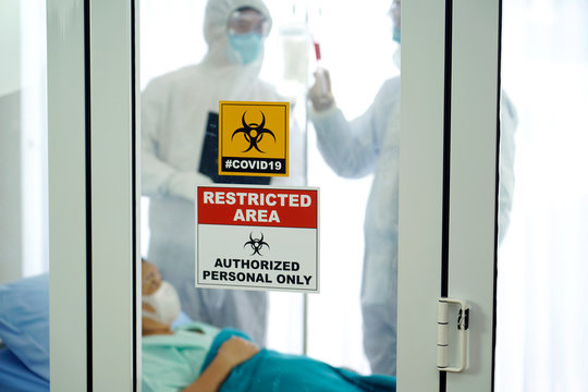 Covid19 control area. Covid19 restricted area signage in front of control area with team of doctor in protective suit are planning to cure the female elderly patient