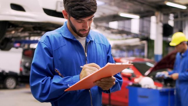 Man specialist an auto mechanic in a car service checks the machine diagnostics check the list of car repairs and lists on the job board.
