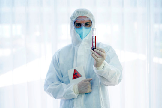 Doctor in personal protective suit showing Coronavirus COVID 19 blood sample tube