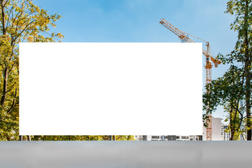 Blank white advertising billboard mockup on a fence of a construction site © diesirae