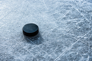 black hockey puck lies on ice at stadium