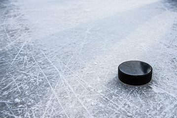 black hockey puck lies on ice at stadium