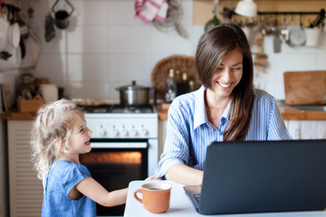 Working mom works from home office. Happy mother and daughter smiling. Successful woman and cute...