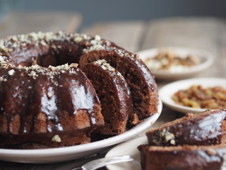 Festive homemade cakes. Round chocolate muffin, large muffin or chocolate icing cake on a wooden ancient background with nuts, raisins, and cinnamon. Place for text.