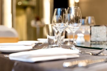 Fototapeta na wymiar Elegant tables set up for banquet, Empty wine glasses, cutlery set knife, spoon, fork and napkin in restaurant