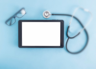 Computer tablet with a white screen on a blue background and glasses for vision, a stethoscope. The...