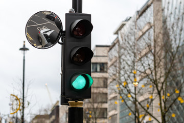 Green Traffic Light Signal and Traffic Convex Mirror with the Reflection of the vehicle, London, England, UK